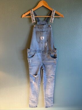 Calvin Klein light blue distressed denim overalls with logo straps